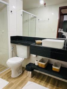 y baño con aseo blanco y lavamanos. en Ap lindo, moderno, confortável, novo!, en Cumbuco
