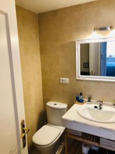 een badkamer met een toilet, een wastafel en een spiegel bij Sanlúcar Playa de las Piletas in Sanlúcar de Barrameda