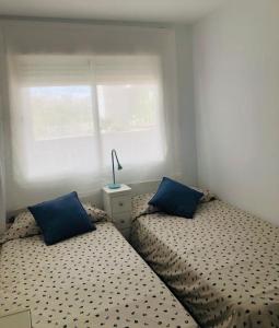 2 bedden met blauwe kussens in een kleine slaapkamer bij Sanlúcar Playa de las Piletas in Sanlúcar de Barrameda