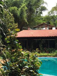 a house with a red roof next to a swimming pool at Espaço Viverde Pousada e Retiros in Brumadinho