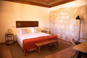 1 dormitorio con cama y pared de piedra en O Pombal en Alcanena