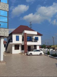 a white car parked in front of a house at BAFFOUR STUDIO in Kumasi