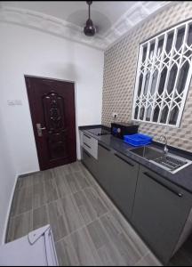 cocina con fregadero y puerta marrón en BAFFOUR STUDIO en Kumasi