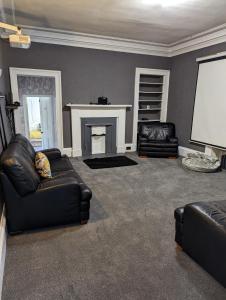 a living room with two leather couches and a fireplace at Bonnyside House in Bonnybridge
