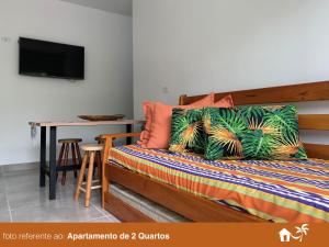um quarto com uma cama com uma mesa e uma televisão em BEIRA MAR - PRAIA Do LÁZARO em Ubatuba