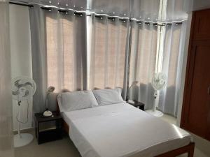 1 dormitorio con 1 cama y ventana con ventilador en Lindo apartamento en el mejor sector de la isla. piscina, bbq, playa a 30 metros en San Andrés