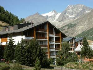 a large building with trees in front of a mountain at Apollo in Saas-Fee
