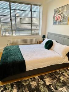 a bedroom with a large bed with a green blanket at Beautiful Quality Apartment in Camden Town in London