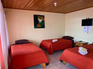 Habitación con 2 camas y una pintura en la pared. en Hotel La Puesta Del Sol B&B, en Monteverde