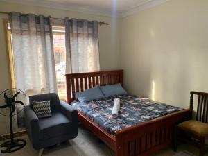 una camera da letto con un letto, una sedia e una finestra di Vine suites a Kampala