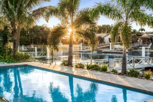 une piscine avec des palmiers dans un complexe hôtelier dans l'établissement Executive Waterfront Home, à Mooloolaba