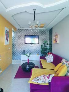 a living room with a purple couch and a tv at Appartement sidi rahal in Berrechid