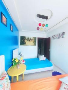 a bedroom with a blue bed and a table at Appartement sidi rahal in Berrechid