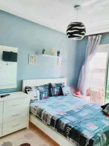 a bedroom with a bed with a blue wall at Appartement sidi rahal in Berrechid