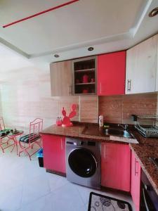 a kitchen with red cabinets and a dishwasher at Appartement sidi rahal in Berrechid