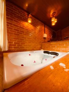 uma banheira branca num quarto com uma parede de tijolos em Pousada, Camping e Restaurante do Sô Ito em Santa Rita de Jacutinga