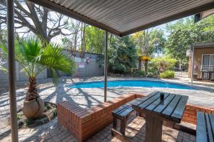 a patio with a picnic table and a swimming pool at Cosy Cottages Guesthouse in Potchefstroom