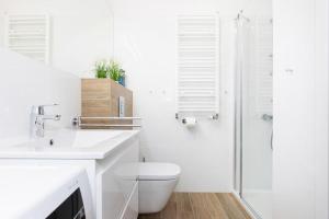 biała łazienka z toaletą i prysznicem w obiekcie OnHoliday Apartamenty ulica Poleska w Kołobrzegu