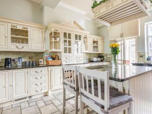una cocina con armarios blancos y una encimera con 2 sillas en Edderton Hall Country House, en Forden