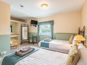 a hotel room with two beds and a mirror at Edderton Hall Country House in Forden