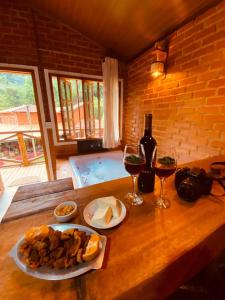 una mesa con un plato de comida y dos copas de vino en Pousada, Camping e Restaurante do Sô Ito en Santa Rita de Jacutinga