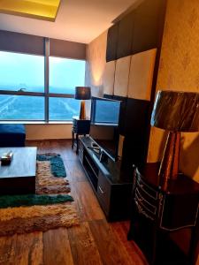 een woonkamer met een televisie en een groot raam bij Royal Residencia Centaurus in Islamabad