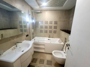 een badkamer met 2 wastafels, een bad en een toilet bij Royal Residencia Centaurus in Islamabad