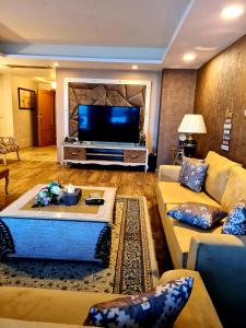 sala de estar con sofá y TV en Royal Residencia Centaurus, en Islamabad