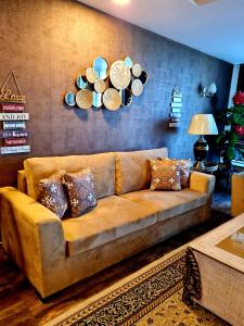 un sofá marrón en una sala de estar con platos en la pared en Royal Residencia Centaurus, en Islamabad