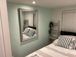 a mirror on a wall next to a bed at 1 bed Home from Home Apartments in London