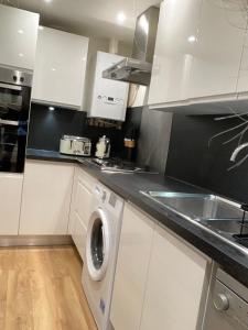 a kitchen with white cabinets and a washing machine at 1 bed Home from Home Apartments in London