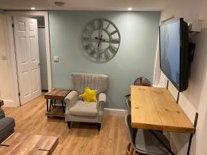 a living room with a table and a clock on the wall at 1 bed Home from Home Apartments in London