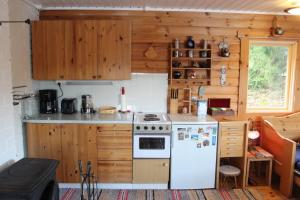a kitchen with a white stove and wooden cabinets at Cozy Cabin by the Lake in Gennarby