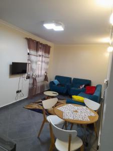 uma sala de estar com um sofá, uma mesa e cadeiras em Ella Apartment Albert Cook Road em Kampala