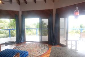 a room with large windows and a large rug at Moonrise Beach in Placencia Village