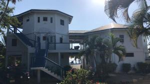 a large white house with stairs and a palm tree at Moonrise Beach in Placencia
