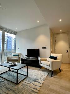 ein Wohnzimmer mit 2 Stühlen und einem TV in der Unterkunft Battersea Power Station Living in London