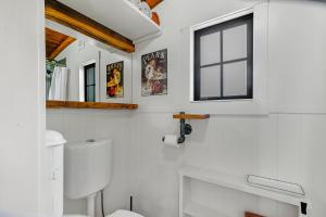 a white bathroom with a toilet and a window at The Shepherds Hut - boutique retreat. in Hanmer Springs