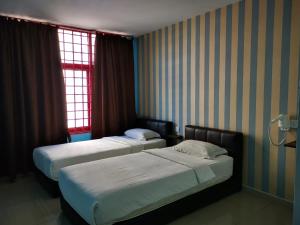 two beds in a hotel room with a window at Parc Hotel Pelangi Damansara in Kota Damansara