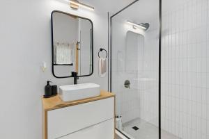 y baño con lavabo, espejo y ducha. en Black River Haus - Scandinavian Riverfront Cabin Muskoka en Washago