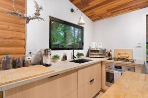 cocina con fregadero y TV en la pared en Black River Haus - Scandinavian Riverfront Cabin Muskoka en Washago