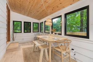 comedor con mesa, sillas y ventanas en Black River Haus - Scandinavian Riverfront Cabin Muskoka en Washago