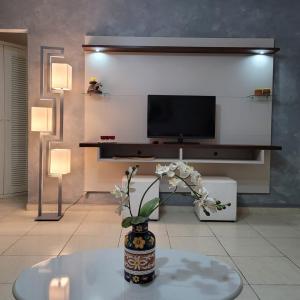sala de estar con TV y jarrón con flores en Geriba Apart Hotel, en Búzios