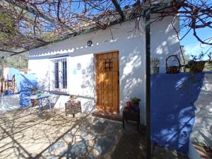 una piccola casa bianca con una porta in legno di El Charcón a Higuera de la Sierra