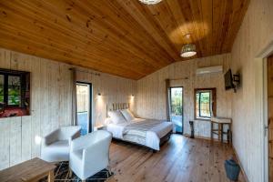 um quarto com uma cama e cadeiras e tectos em madeira em le lodge en mormal em Louvignies-Quesnoy