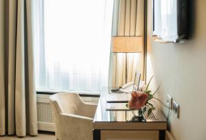 a room with a desk with a laptop and a chair at Althoff Hotel am Schlossgarten in Stuttgart