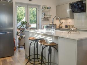 a kitchen with a counter with stools in it at Primrose Cottage - Uk41346 in Cromer