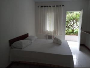 een witte slaapkamer met een groot bed en een raam bij Casa Brasil pousada e lazer in Trindade