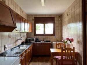 a kitchen with wooden cabinets and a table and a microwave at Casa la Pineda Salou, playa y Port Aventura in Salou