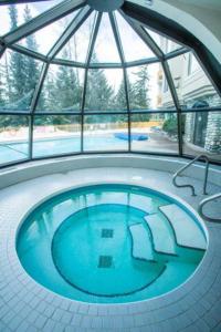 a large swimming pool in a building with a window at 1BR Ski In Ski Out Cozy Condo w Pool and Hot Tub by Harmony Whistler in Whistler